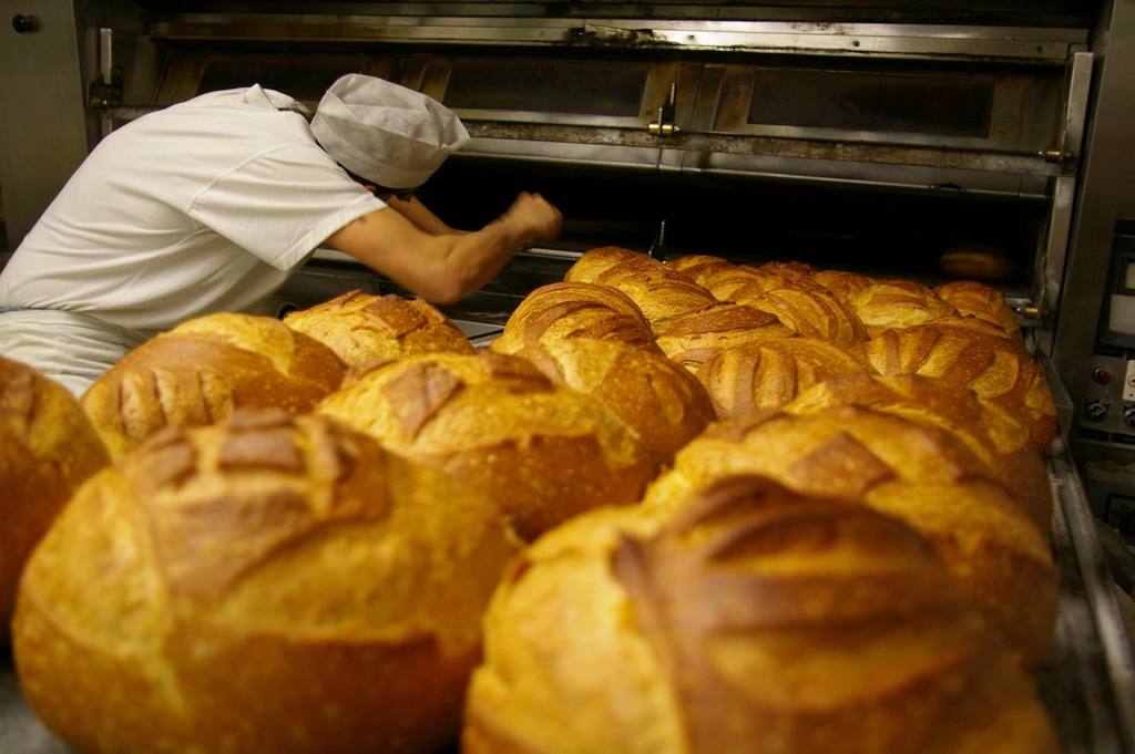 De bakker haalt vers brood uit de oven